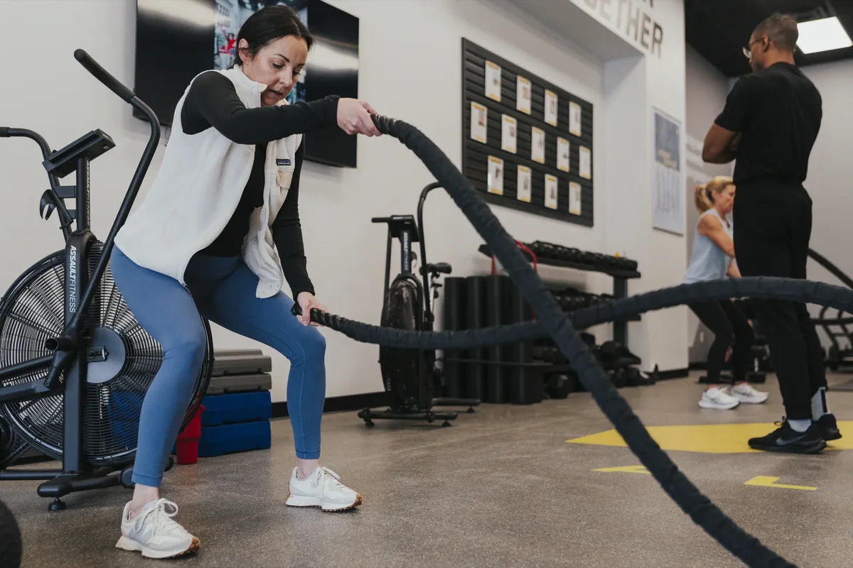 A member powers through battle rope work during a small group session at an Alloy Personal Training studio
