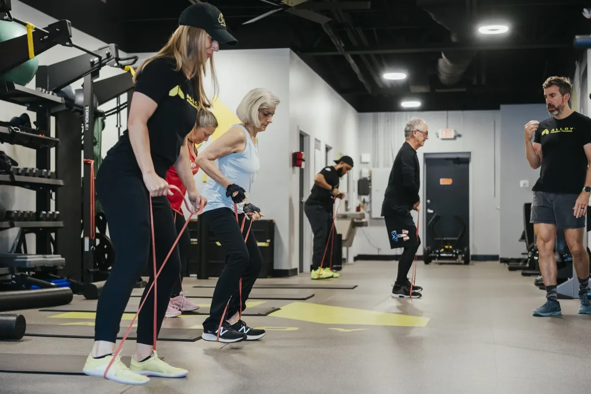 Older adults work through banded hinge drills with coaches during a small group session