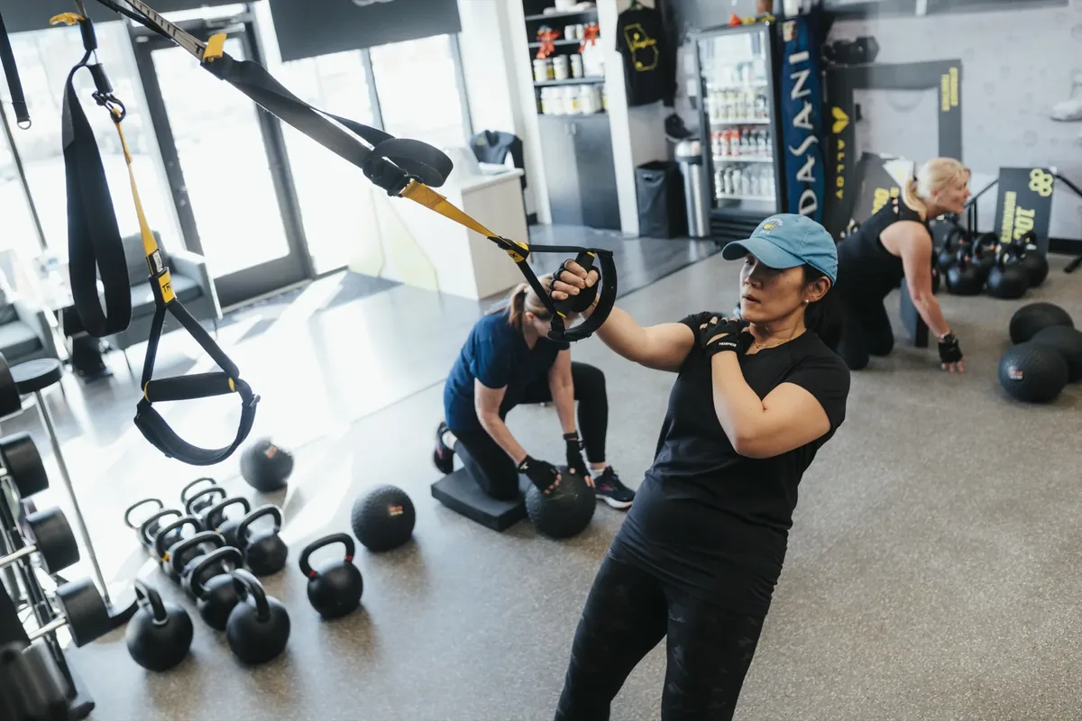 Members work suspension trainers and floor drills during a coached small group session
